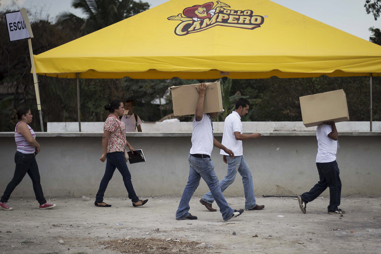 Un grupo de personas con gafetes de “coordinadores” cargan cajas llenas de comida rápida para proporcionar a los asistentes.