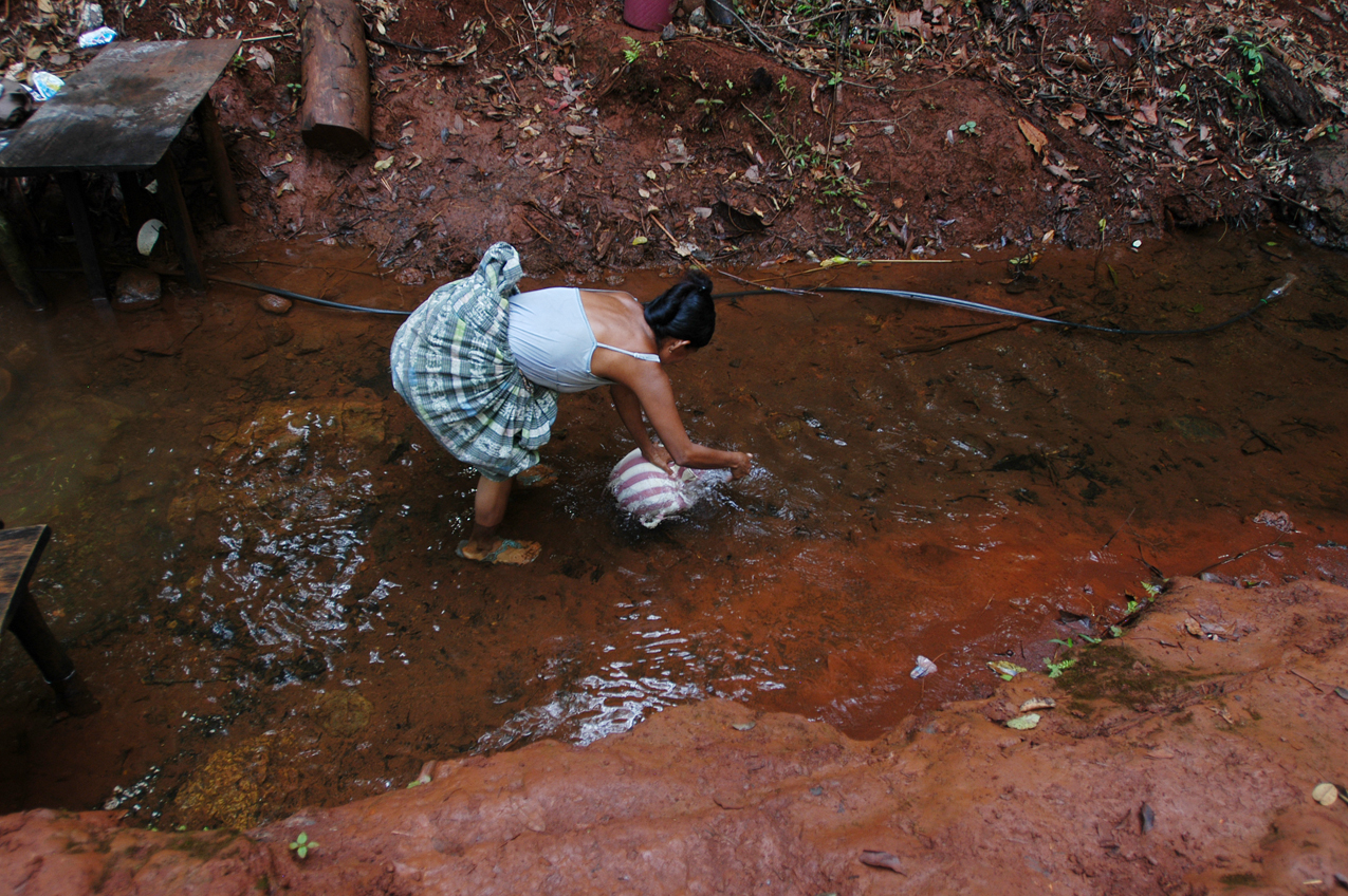 Una mujer recoge agua cerca de la zona de explotación de niquel.