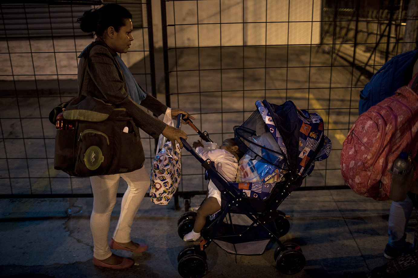 Una madre lleva la hija de pocos meses en el carruaje, acomodada entre paquetes y ropa