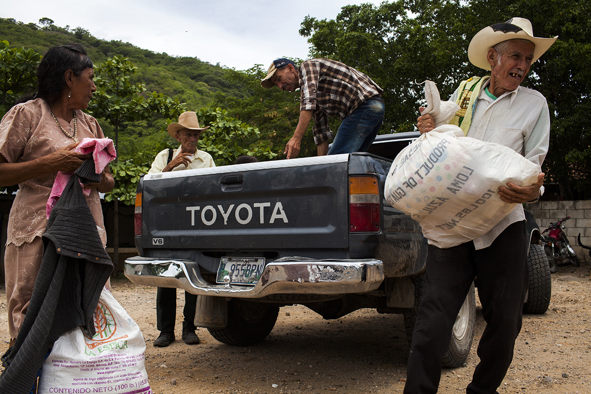En la aldea Los Olotes, los costales de alimentos transportados en picop son recibidos por los hombres de la comunidad 