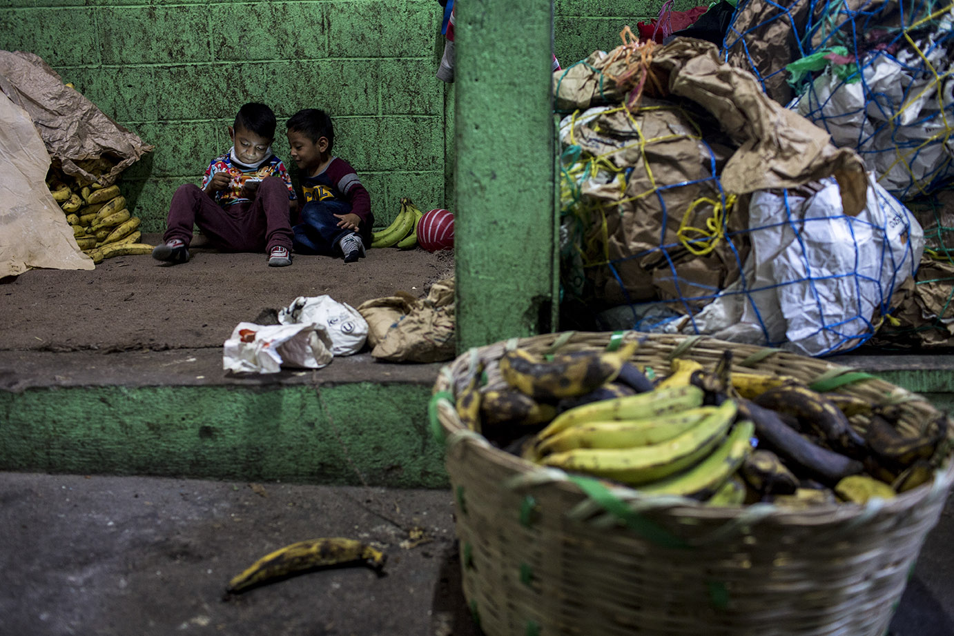 Dos niños, originarios de Santa Cruz El Quiché, juegan en la platanera del mercado de la Terminal, donde trabajan sus padres. Simone Dalmasso