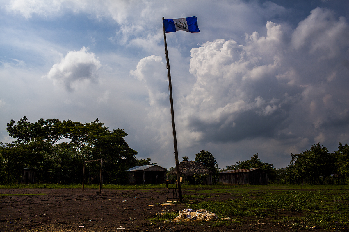 En el medio del campo de fútbol, al lado de la escuela, la bandera nacional flamea al viento quemador de las primeras horas de la tarde.